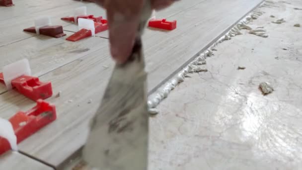 Un operaio sta livellando la piastrella di ceramica con cunei e clip. Sistema di livellamento piastrelle, — Video Stock