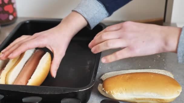 Bir kadın sosisli sandviç için ekmek keser ve bir kase koyar. — Stok video