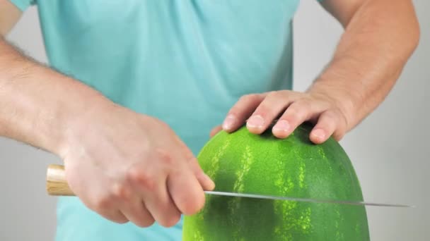 Ein Mann zieht eine Wassermelonenmütze aus. Ein Mann schneidet eine Wassermelone im Kreis und schneidet eine Wassermelone — Stockvideo