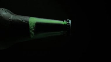 İtalya, Roma - 23. 06 numara. 2021 dikey video. Yeşil Heineken birasının kapağı siyah arka planda dönüyor. Görüntüleri ayır. Alman birası ayna masasında kendi etrafında döner..