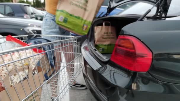 Италия, Рим. 2 июля 2021 года. Женщина кладет бумажные пакеты из магазина в багажник машины — стоковое видео