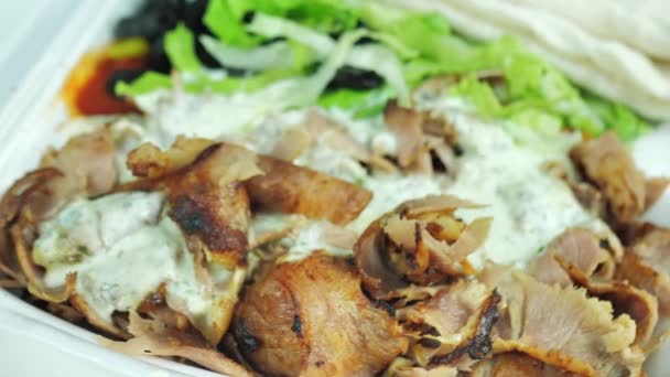 Kebab, gyros, shawarma na desce, zapakowane w jednorazowe opakowanie. Obraca się na talerzu. Ruch cykliczny — Wideo stockowe