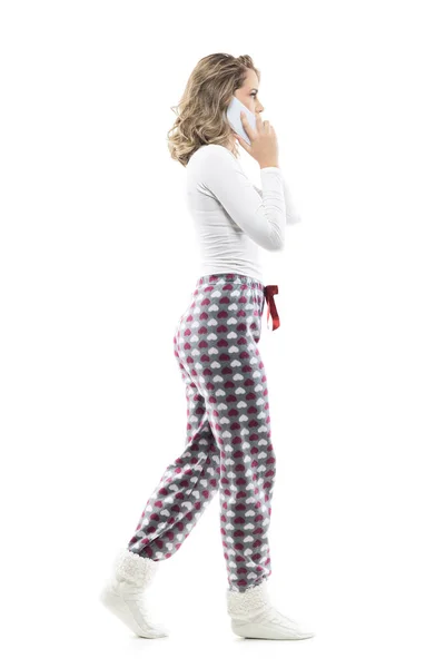 穿着睡衣 一边走路一边用手机说话的女人的侧视图 在白色背景上隔绝的全身上下 — 图库照片