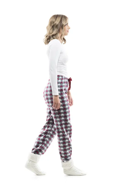 パジャマと冬の靴下を着た若いきれいな女性が歩いて先を見ています サイドビュー 白い背景に隔離された全身の長さ — ストック写真