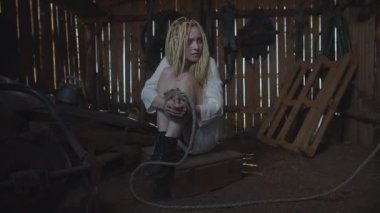 Dehşete düşmüş, elleri barakada bağlı bir kadın.