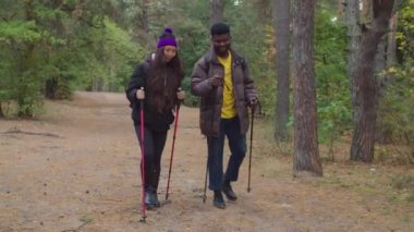 Sonbahar ormanlarında yürüyüş yapan neşeli, çok kültürlü bir çift.