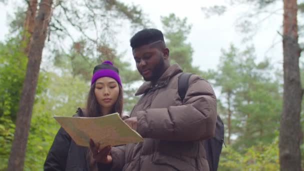 Multietniskt par läser karta under backpacking — Stockvideo