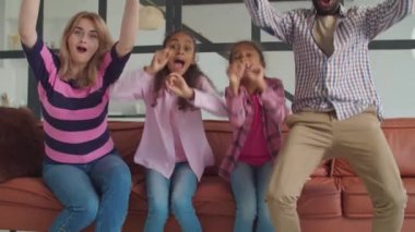 Aile televizyonda maç izleyip golü kutluyor.