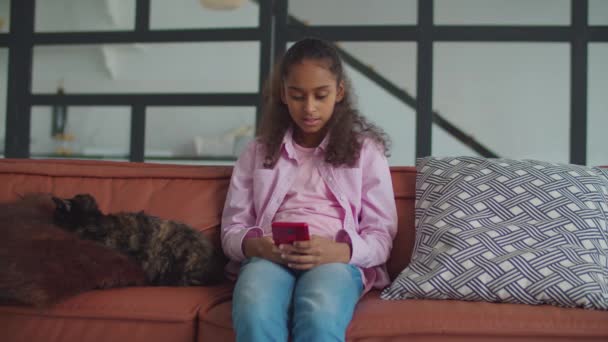 Nastolatka online wiadomości na telefon komórkowy na kanapie — Wideo stockowe