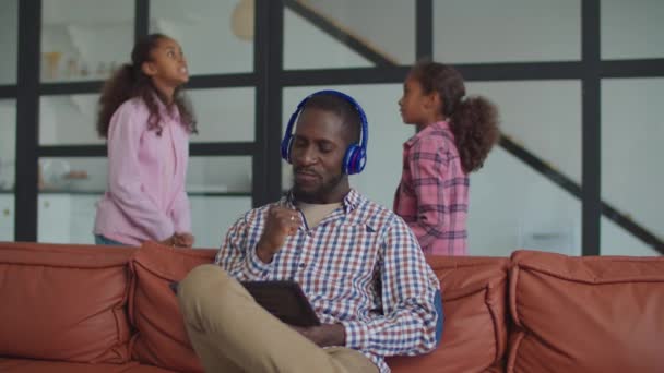 Padre negro en auriculares disfrutando de la música en el sofá — Vídeos de Stock