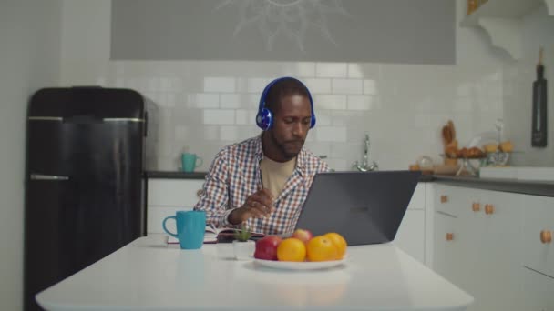 Чорний чоловік в навушниках дивиться вивчаючи вебінар — стокове відео