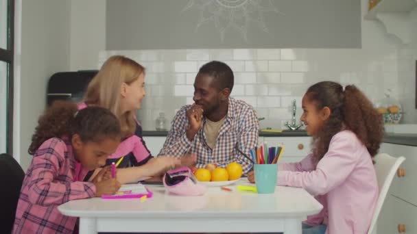 Счастливая семья с девочками, наслаждающимися отдыхом на кухне — стоковое видео