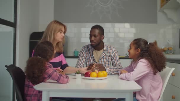 Прекрасная многонациональная семья, молящаяся за кухонным столом — стоковое видео