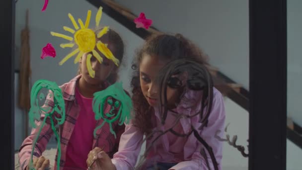 Roztomilé černošky holčičky malování na okno sklo — Stock video