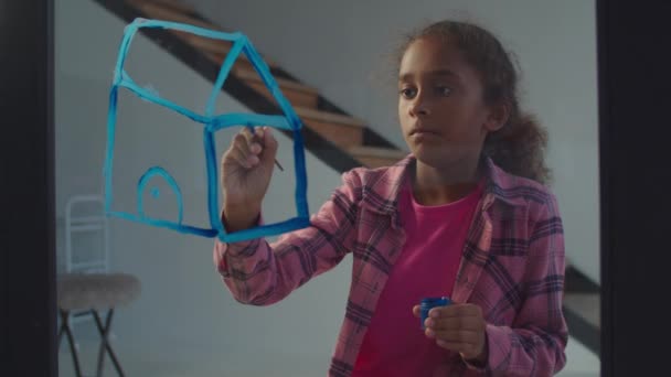 Маленький черный художник рисует дом мечты на стекле — стоковое видео