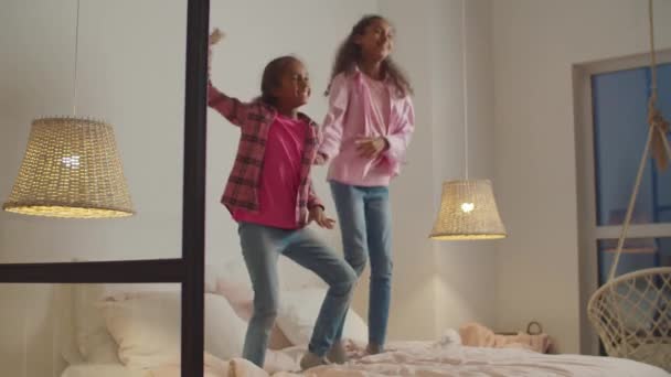 Verspielte schwarze vorpubertäre Schwestern springen auf Bett — Stockvideo