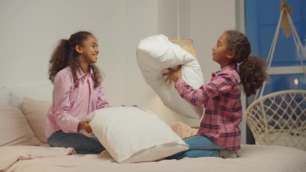 Black preadolescent sisters pillow fighting on bed — Stock Video