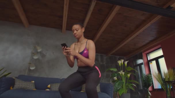 Female online messaging on phone during exercise — Wideo stockowe