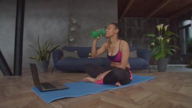 Sportif formda, laptoplu kadın antrenmandan sonra dinleniyor.