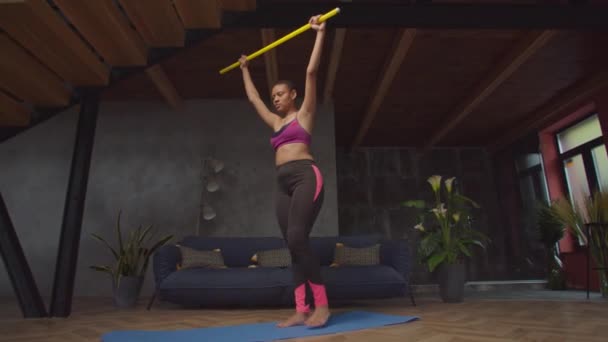 Fit female exercising glute kickback with bar — Stock Video