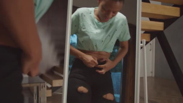 Μαύρο θηλυκό προσπαθεί να χωρέσει σε στενά τζιν σε εσωτερικούς χώρους — Αρχείο Βίντεο