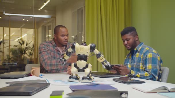 Ingenieros africanos con tablet PC manipulando robot — Vídeos de Stock