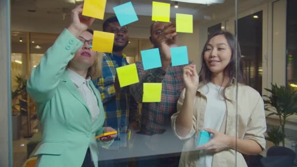 Business team schrijven ideeën over plakkerige notities op glas — Stockvideo