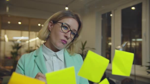 Kvinnlig chef skriva idéer om klistermärken i kontoret — Stockvideo