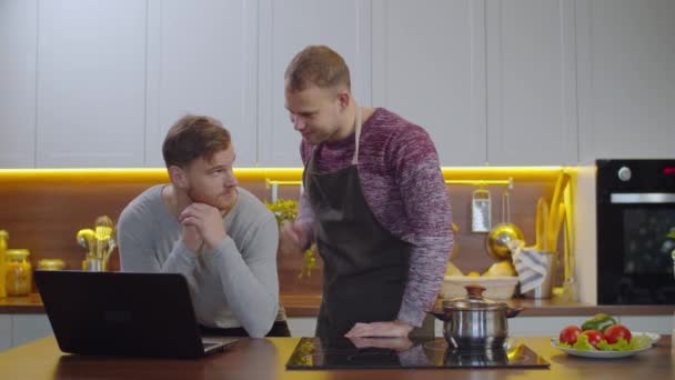 Feliz pareja gay relajándose en la cocina durante la cocina — Vídeo de stock