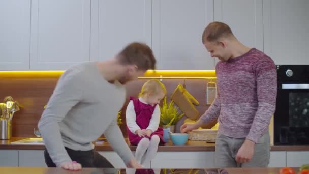 Neşeli eşcinsel ebeveynler ve küçük kız mutfakta oynuyorlar. — Stok video