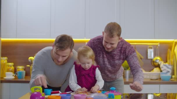 Caring gay parents with kid playing game indoors — Stock Video