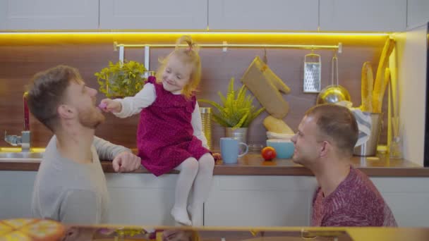 Podekscytowany dziecko karmienie radosny gej rodzice w kuchnia — Wideo stockowe