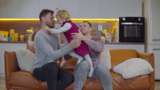 Happy same sex family and daughter bonding on sofa — Stock Video