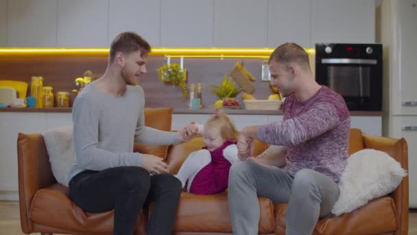 Heureux gosse tenant gay parents mains sauter sur canapé — Video