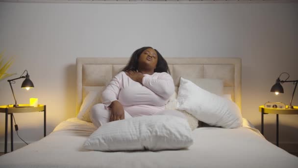 寝る前にベッドの上でストレッチ疲れアフリカの女性 — ストック動画