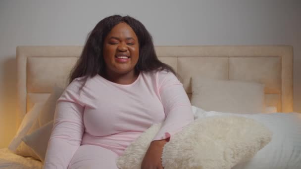 Positiva femmina in pigiama seduta sul letto ridendo — Video Stock