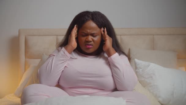 Mujer con dolor de cabeza en la cama que masajea las sienes — Vídeos de Stock