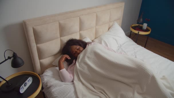 Vild kvinna vaknar upp och sträcker ut armarna i sängen — Stockvideo
