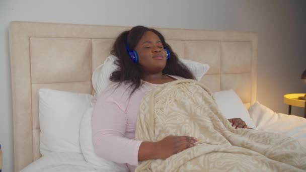 Mujer relajada en auriculares disfrutando de la música en la cama — Vídeo de stock