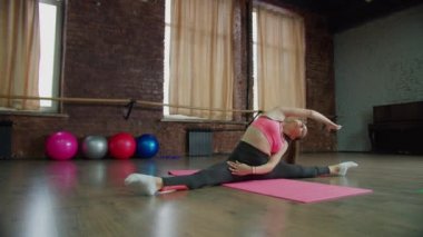 Sağlıklı bir kadın yan yana oturur ve içeride egzersiz yapar.