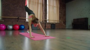 Spor formundaki kadın içeride esneme egzersizi yapıyor.