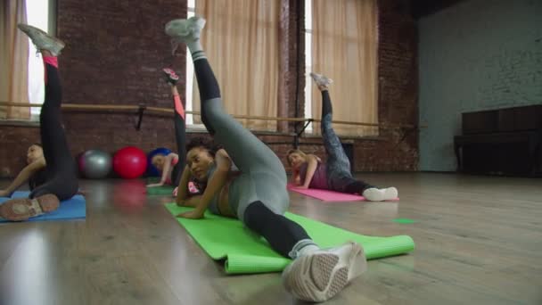 Multiétnico deportivo en forma de las mujeres haciendo levantamientos de piernas laterales — Vídeo de stock