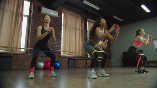 Diverse fitte Frauen machen Kniebeugen mit Widerstandsband — Stockvideo