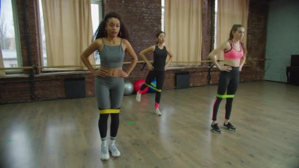 Fitness vrouwen doen banded standing kickbacks in de sportschool — Stockvideo