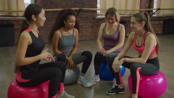 Groupe de femmes sportives se détendre sur des balles d'exercice à la salle de gym — Video