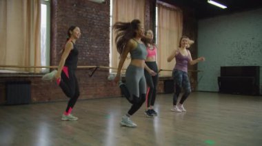 Kaygısız sporcu kadınlar dans stüdyosunda egzersiz yapıyor.
