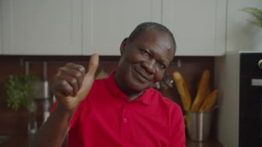 Yakışıklı, kıdemli, Afrikalı bir adam içeride başparmak kaldırıyor.