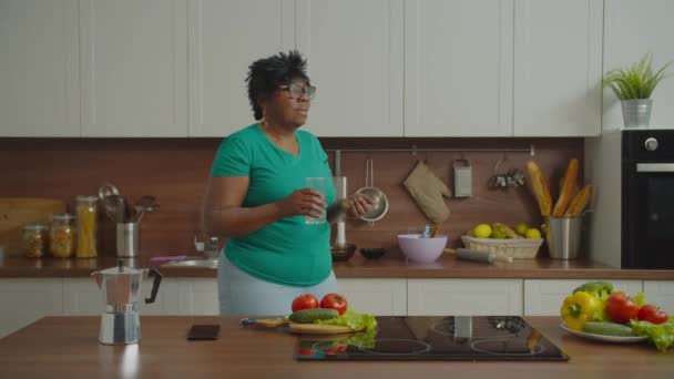 Sairas kypsä musta nainen ottaa pillereitä keittiössä — kuvapankkivideo