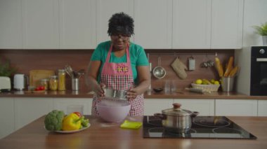 Emekliye ayrılmış Afrikalı kadın süzgeçten un geçiriyor.