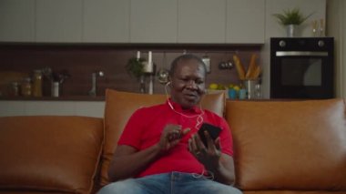 Evde müzik dinleyen üst düzey siyahi adam.